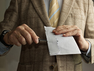 Hombre con traje y corbata abre un sobre con una navaja o un abrecartas.