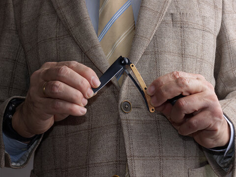 Hombre con traje y corbata abre una peque&ntilde;a navaja de bolsillo.