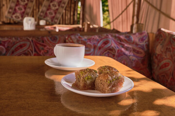 Eastern sweetness, Turkish baklava, black coffee in a white cup on a wooden table.