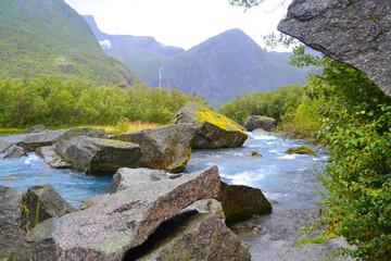 Beautiful landscape of Norway with huge mountains, waterfall and azure river. Big rocks on the...