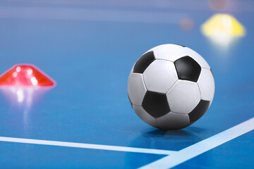 Classical Soccer Ball on Indoor Floor. Futsal Training Field. Training Matkers in the Blurred Background. Indoor Football Equipment