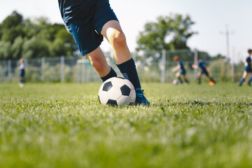 Junior Level Football Player Kicking Ball. Legs of Soccer Striker Playing Training Game. Closeup Image of Sports Athlete Running Ball. Soccer Training Session