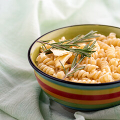Boiled fusilli pasta with rosemary in a plate on table