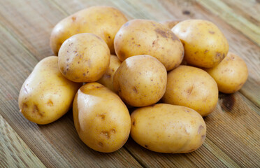 Naklejka na ściany i meble Closeup of fresh organic potatoes on wooden surface. Healthy vegetarian ingredient
