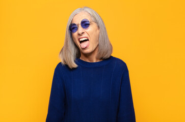 middle age woman with cheerful, carefree, rebellious attitude, joking and sticking tongue out,...