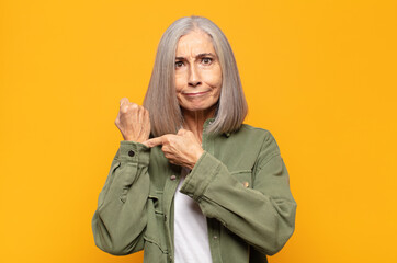 middle age woman looking impatient and angry, pointing at watch, asking for punctuality, wants to...