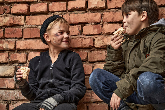 Smiling Street Kids Eating Food, Smiling. Little Poor Children Enjoy Meal, Have No Shelter And Money