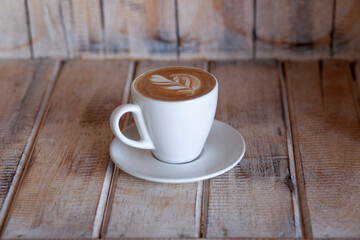 A white cap of coffee with foam on wooden backgraund