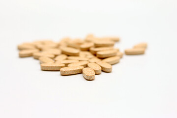 Pile of vitamins pills scattered on white background