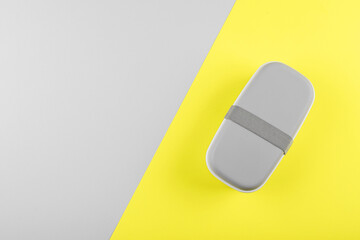 Gray lunch box on gray yellow background. Concept of color of the year 2021