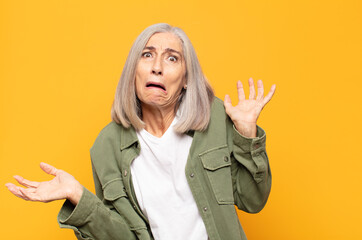 middle age woman shrugging with a dumb, crazy, confused, puzzled expression, feeling annoyed and...