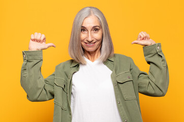 middle age woman feeling proud, arrogant and confident, looking satisfied and successful, pointing...