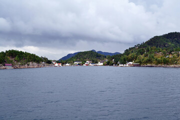 Norwegian fjord and mountains in cloudy summer day. Mountain rural landscape village view during a boat trip, Lysefjord, Norway. 