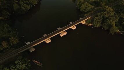 Drone aerial view of narrow gauge railway bridge over waterway during soft evening sunlight in Asia - Powered by Adobe