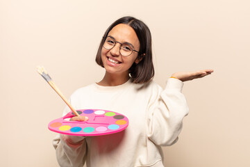 young hispanic woman smiling happily with funny face, joking and looking through peephole, spying...