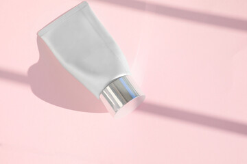 Mock-up of plastic tube, hand cream isolated on pale pink background.