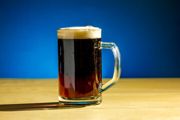 A mug of  beer stands on the table on a blue background