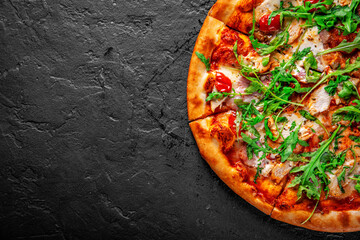 Pizza mit Huhn, Speck, Käse, Tomaten und Rucola. Italienische Pizza auf dunkelgrauem schwarzem Schieferhintergrund