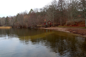 A nice view over a beach shore with a red house during the winter. Before the snow. Calm water. Järfälla, Stockholm, Sweden.