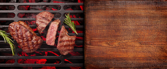 Beef steaks cooking on grill - obrazy, fototapety, plakaty