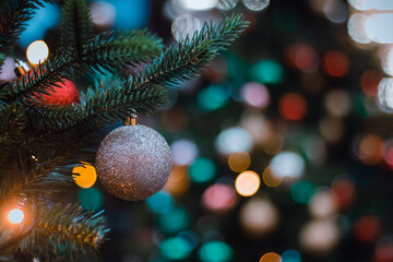 Obraz na płótnie Canvas Brown silver glass ball on Christmas tree big on blurry colorful background. Selective focus