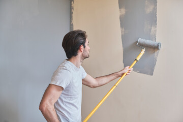 Young handsome man painting his walls