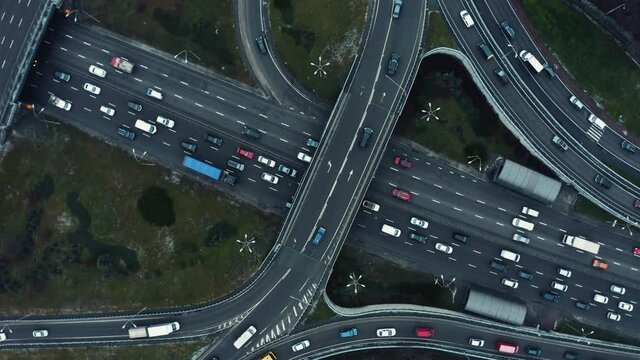The movement of cars at crossroads in city, aerial view. Aerial view of the highway crossing. Drone shot flying over crossing roads. Huge road junction full of cars and trucks. Traffic jam