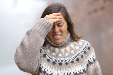 Adult woman suffering head ache in a park in winter