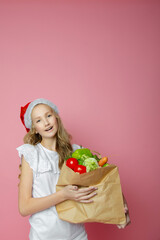 cute girl on a pink background with vegetables and fruits in a medical mask