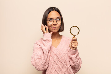 young hispanic woman scheming and conspiring, thinking devious tricks and cheats, cunning and...