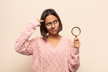 young hispanic woman with a serious and concentrated look, brainstorming and thinking about a...