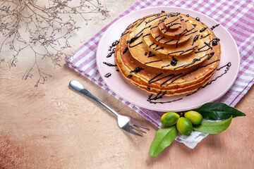 Side view of classic delicious pancakes decorated with chocolate syrop on pink stripped towel