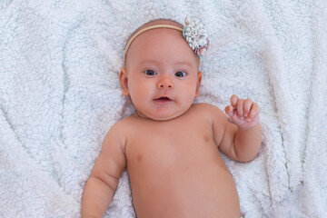 Newborn baby girl with a bandage on her head smiling cute. Top view