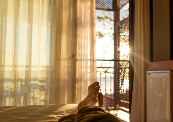 lying and relaxing in bed opposite a window at sunset