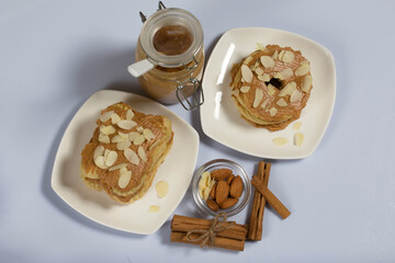 Eclairs cake smeared with cinnamon cream. Nearby ingredients for cooking. On a white surface.