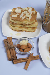 Eclairs cake smeared with cinnamon cream. Nearby ingredients for cooking. On a white surface.