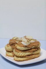 Eclairs cake smeared with cinnamon cream. On a white surface.