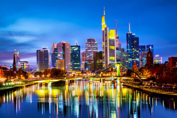 Fototapeta na wymiar Panoramic view cityscape skyline of business district with skyscrapers and mirror reflections in the river Main during sunset blue hour, Frankfurt am Main. Hessen, Germany