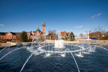A beautiful fountain in a small city park with a brilliant blue sky.