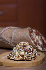 An energy bar made of dried fruits, nuts and seeds. Wrapped in edible paper. The wax seal is visible. On black pine boards.