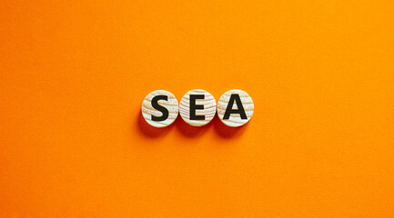 SEA symbol. Concept word 'SEA - search engine advertising' on wooden circles on a beautiful orange...