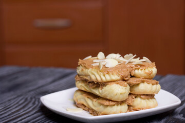 Eclairs cake smeared with cinnamon cream. On black pine boards.