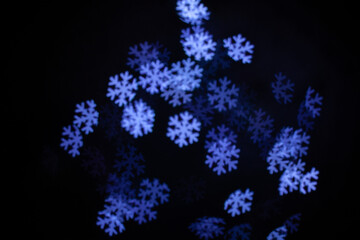 Fototapeta na wymiar Christmas lights in the form of snowflakes. Blurred background. Flashing abstract colored circles defocused Christmas light video. Blurred fairy lights