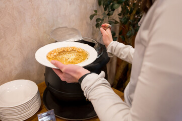 Detail view of woman pouring soup at buffet.