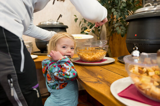 Cute girl with her mother at food buffet getting soup.