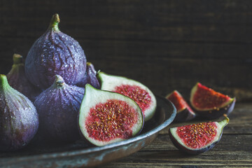 Cut and whole figs on dark, wooden background