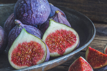 Cut and whole figs on dark, wooden background