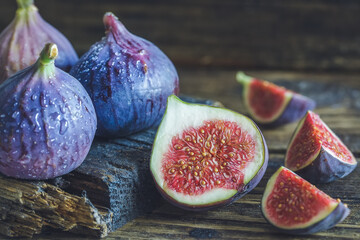 Cut and whole figs on dark, wooden background