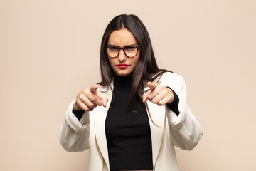 young hispanic woman pointing forward at camera with both fingers and angry expression, telling you...