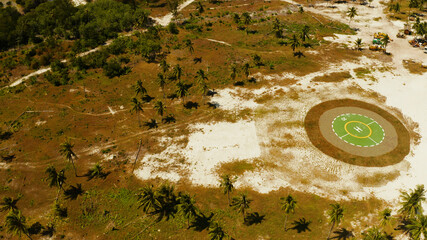 Helipad among the palm trees on a tropical island top view. Helicopter landing site. Bugsuk island, Balabac, Palawan